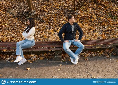 Frowning Young Couple In Quarrel Guys Are Sitting On Bench Stock Image