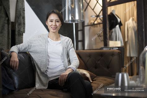 Chinese Clothing Store Owner Sitting On Sofa Shop Indoors Stock