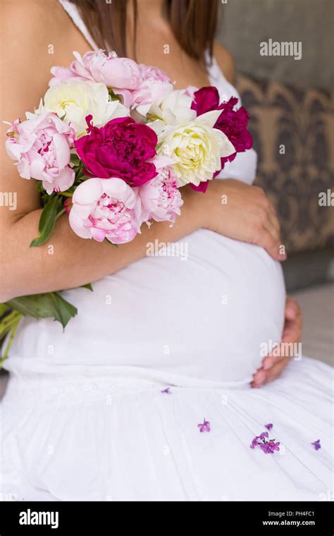 Close Up Image Of Pregnant Woman In Nice White Dress Touching Her Belly With Hands And Holding A