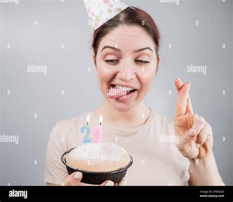 happy caucasian woman sticking out her tongue and blowing out the candles on the cake with her