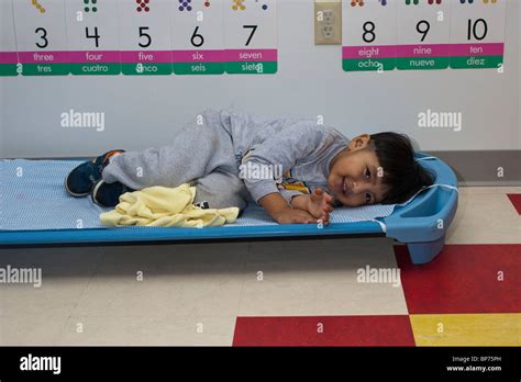 4 Year Old Preschool Boy Lying On A Cot During Nap Time At School Stock
