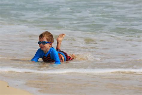 Rapaz Pequeno Que Joga Com As Ondas Na Praia Da Areia Imagem De Stock