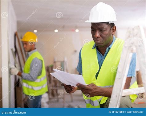 African American Man Construction Worker Holding Document In Hand While
