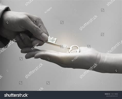 Close Up Hand Of Businessman Giving A Key To Woman Hand With Black And