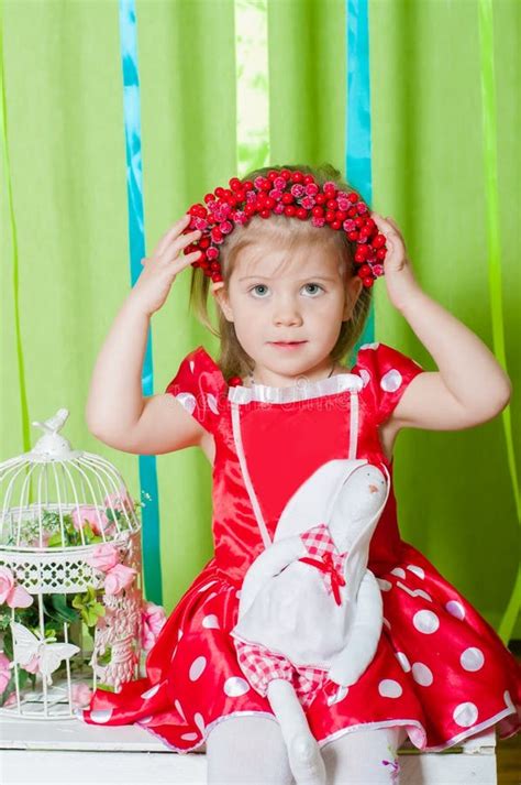 Beautiful Little Girl In A Red Dress With A Red Heart Pillow Stock