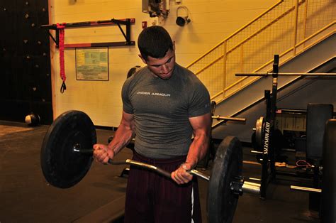 Muscular Man Doing Barbell Curls Exercise