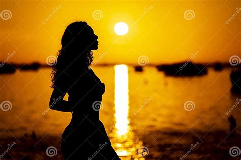 A Lovely Nude Latin Model Is Silhouetted As She Poses With The Rising Sun Behind Her On A