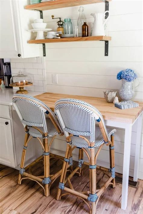 Two Wicker Bar Stools Sitting Next To A Wooden Table In A Small Kitchen
