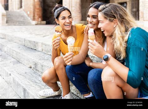 Happy Multiracial Women Eating Ice Cream Outdoors While Sitting At The Stairs Stock Photo Alamy