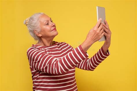 Caucasian Woman Makes A Selfie Studio Shot On Yellow Wall Stock Photo