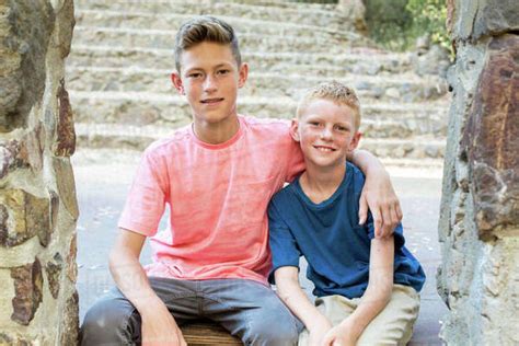 Older Brother With Arm Around Younger Brother Sit For Portrait Stock