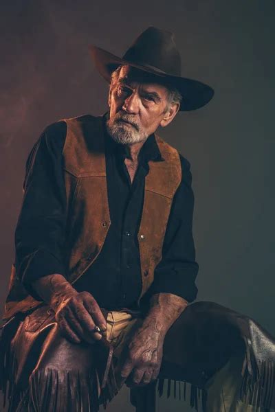 Old Rough Western Cowboy With Gray Beard And Brown Hat Holding R