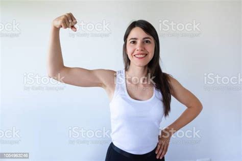 Smiling Sporty Girl Flexing Her Bicep And Looking At Camera Stock Photo
