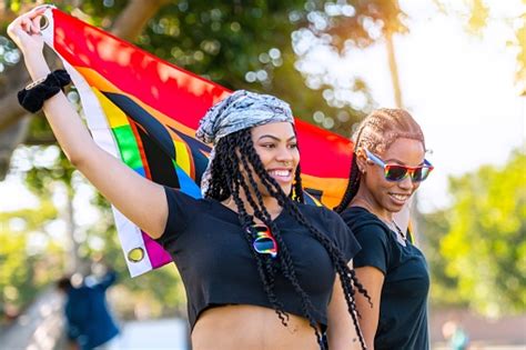 afrolatinx junge lesben die ein regenbogenbanner mit dem wort proud darauf halten stockfoto und