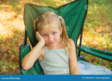 Beautiful Blond Blue Eyes Little Girl Sitting On A Chair In Yard Or