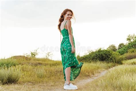 Girl Wearing Summer Dress Walking In A Meadow During Sunset Stock Photo