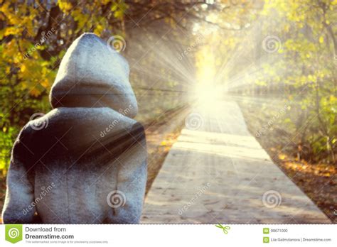 Person In A Hood Walking Toward The Light Stock Photo