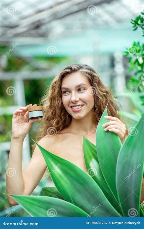 Naked Woman Holding A Jar Of Facial Cream And Looking Joyful Stock