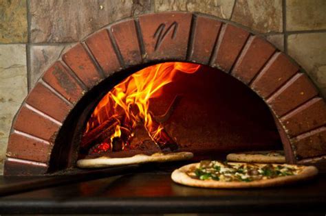 Pizza maker holding peel crest woodcut. Our Brick Oven - Bella Napoli Pizzeria