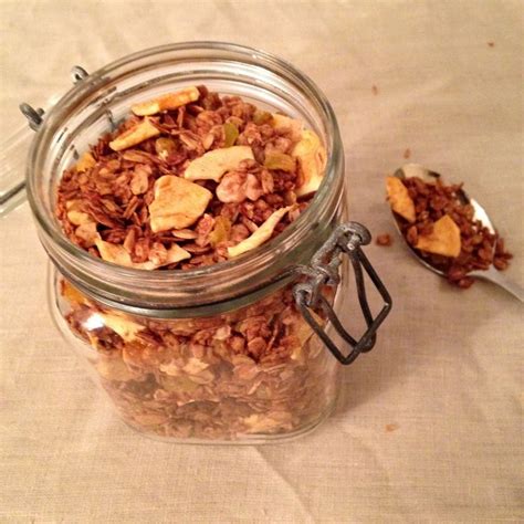 A Glass Jar Filled With Granola Sitting On Top Of A Table Next To A Spoon