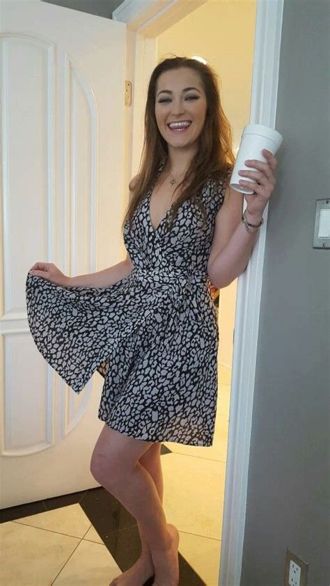 A Woman Standing In Front Of A Door Holding A Cup And Posing For The Camera