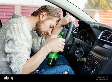 Young Drunk Man Fall Asleep Behind The Wheel Of A Car Male Car Driver Holding Bottle Of Beer