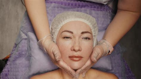 Woman Receiving Facial Massage In Spa Salon On Massage Table Wellness