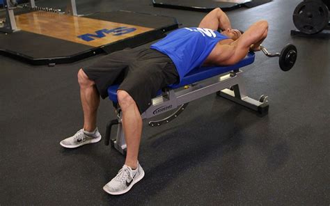 A Man Laying On Top Of A Bench With A Barbell In Front Of Him
