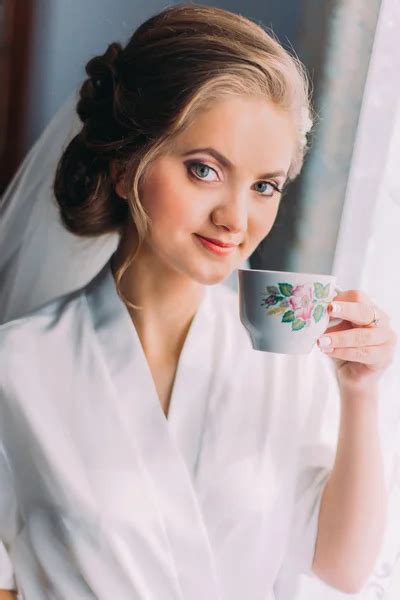 Close Up Portrait Of Beautiful Bride Posing In Robe And Drinking From