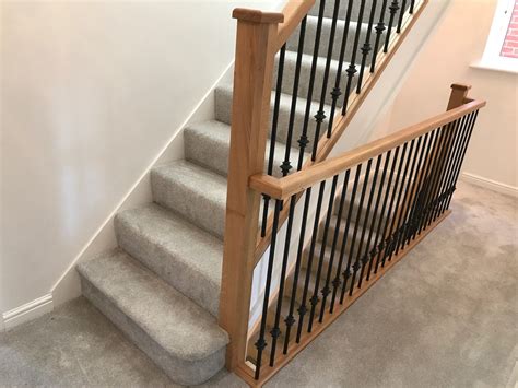 This selection of staircase items includes three curved wooden banister pieces and fifteen twist motif wrought iron spindles with swirled accent. Oak, Metal Spindles - Edwards & Hampson
