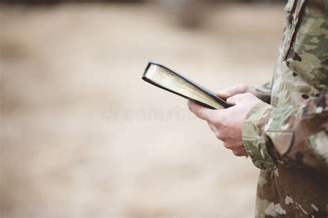Shallow Focus Shot Of A Young Soldier Holding A Bible In A Field Stock