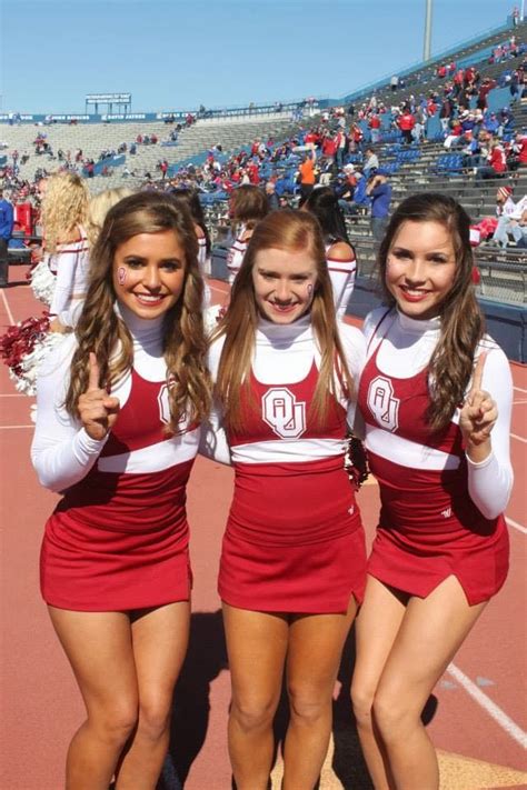Three Cheerleaders Posing For The Camera At A Football Game