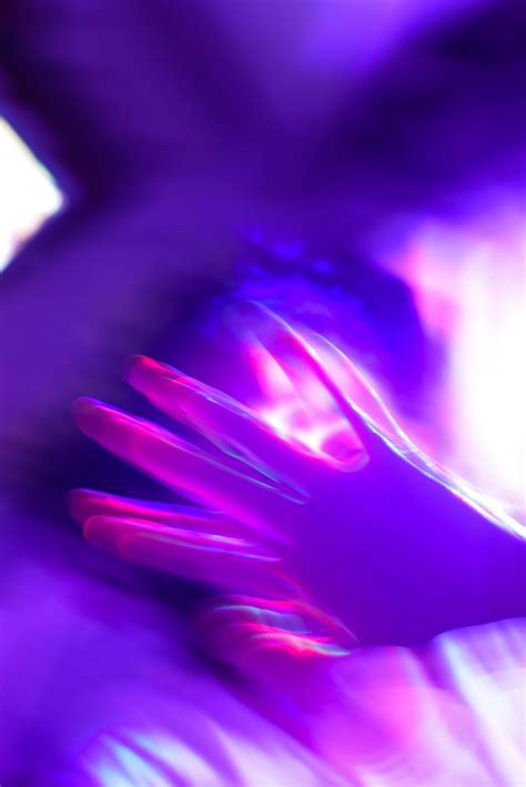 a blurry image of a person s hands with purple and pink lights in the background