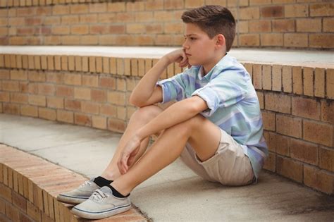 Premium Photo Sad Schoolboy Sitting Alone On Steps In Campus