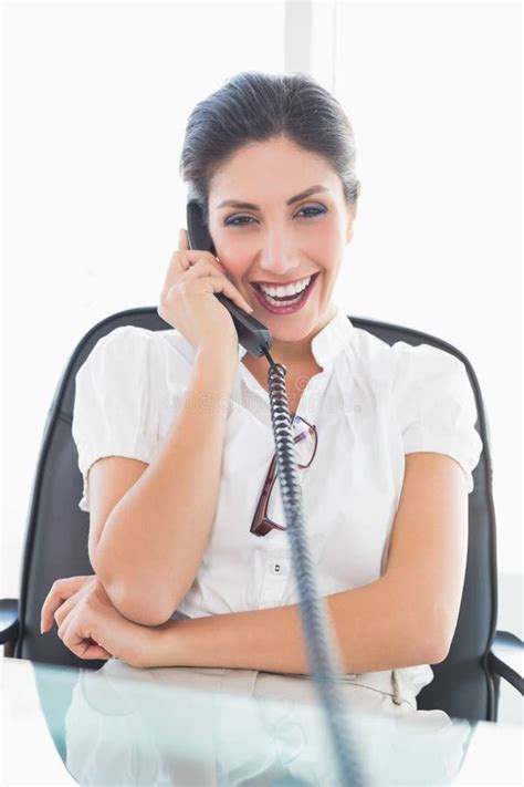 Laughing Businesswoman Sitting At Her Desk On The Phone Stock Photo