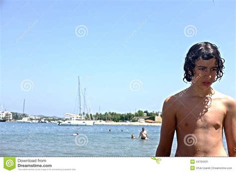 Muchacho Adolescente Joven Que Se Coloca En La Playa Imagen De Archivo