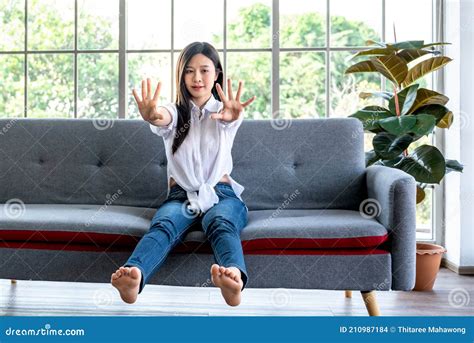 Woman Sitting On A Sofa Stretching Her Arms And Legs To Relax The Muscles And Prevent Sick