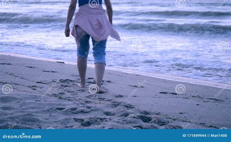 A Girl In Blue Jeans And A Pink Jacket Tied On Her Belt Came To The Sea