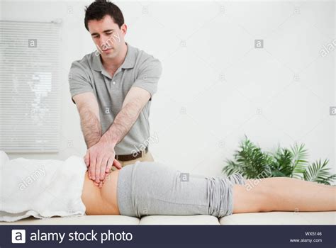 Masseur Standing While Massaging The Back Of His Patient In A Room