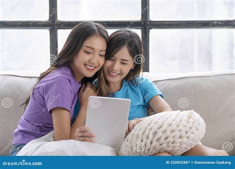 Happy Asian Lgbtq Lesbian Woman Looking Tablet Sitting Together Pillows On Sofa Living Room