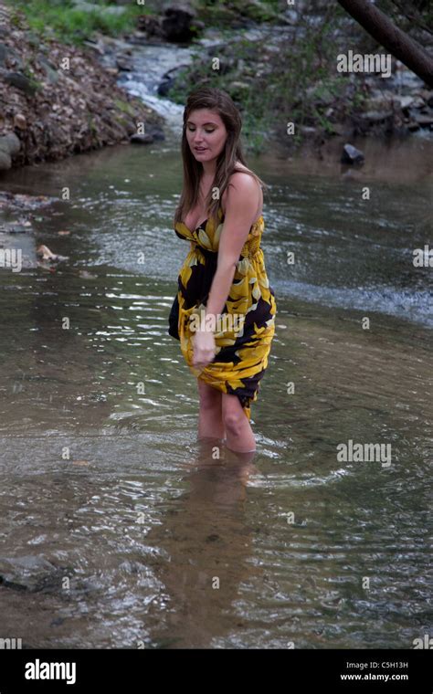 Pretty Woman In Yellow Dress Wading In A Shallow Creek Stock Photo Alamy