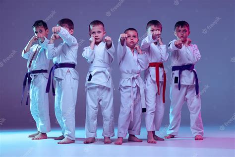 grupo de meninos crianças treinando karatê de artes marciais isolado sobre fundo de estúdio roxo