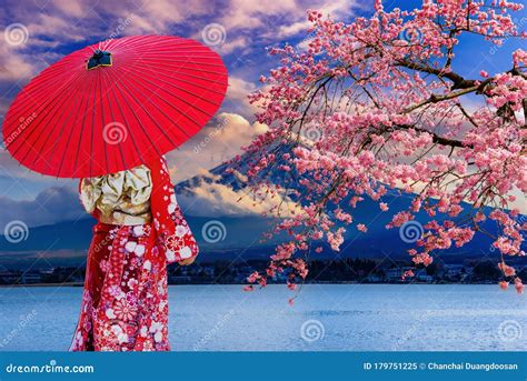 Asian Women Wear Japanese Kimonos Holding A Red Umbrella At Mount Fuji