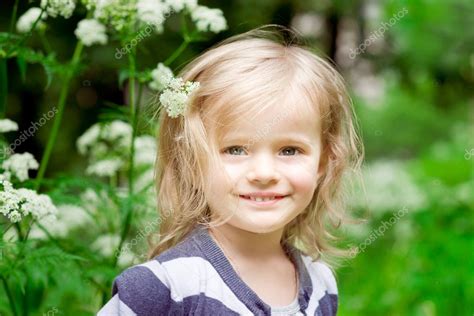 adorable niña pequeña rubia sonriente con flor en el pelo en día de verano — foto de stock