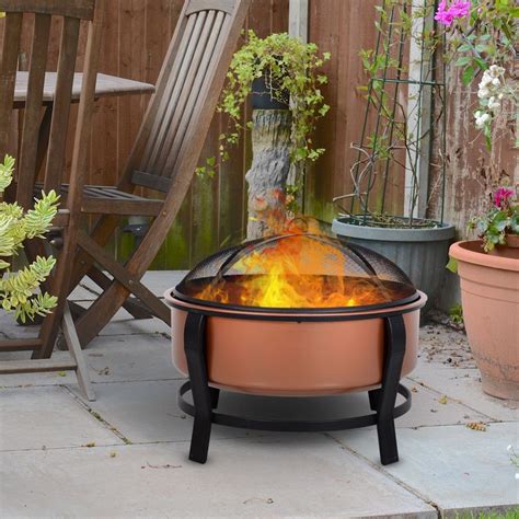 An Outdoor Fire Pit Sitting In The Middle Of A Yard Next To Chairs And