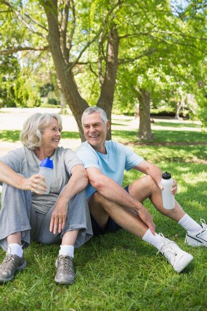 Premium Photo Mature Couple Sitting With Water Bottles At Park