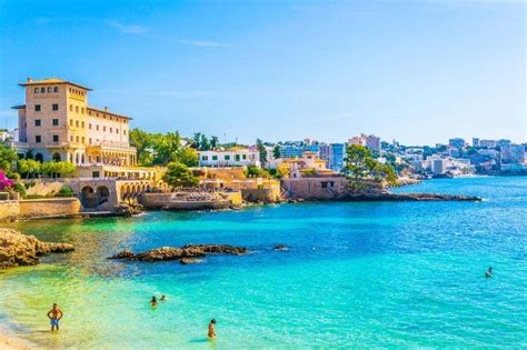 People Are Swimming In The Blue Water Near A Beach With Buildings And