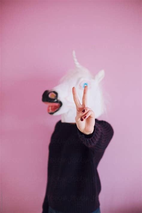 Young Woman With Unicorn Mask Showing A Piece Sign Del Colaborador De Stocksy Jovana Rikalo