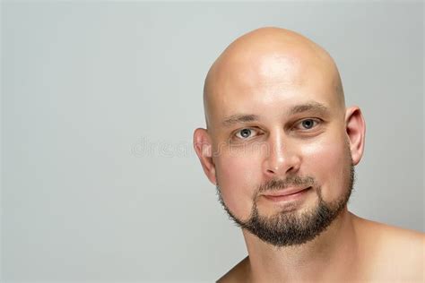 Attractive Smiling Bald Man On Gray Background In Studio Stock Photo