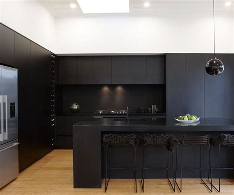 A Modern Kitchen With Black Cabinets And Stainless Steel Appliances
